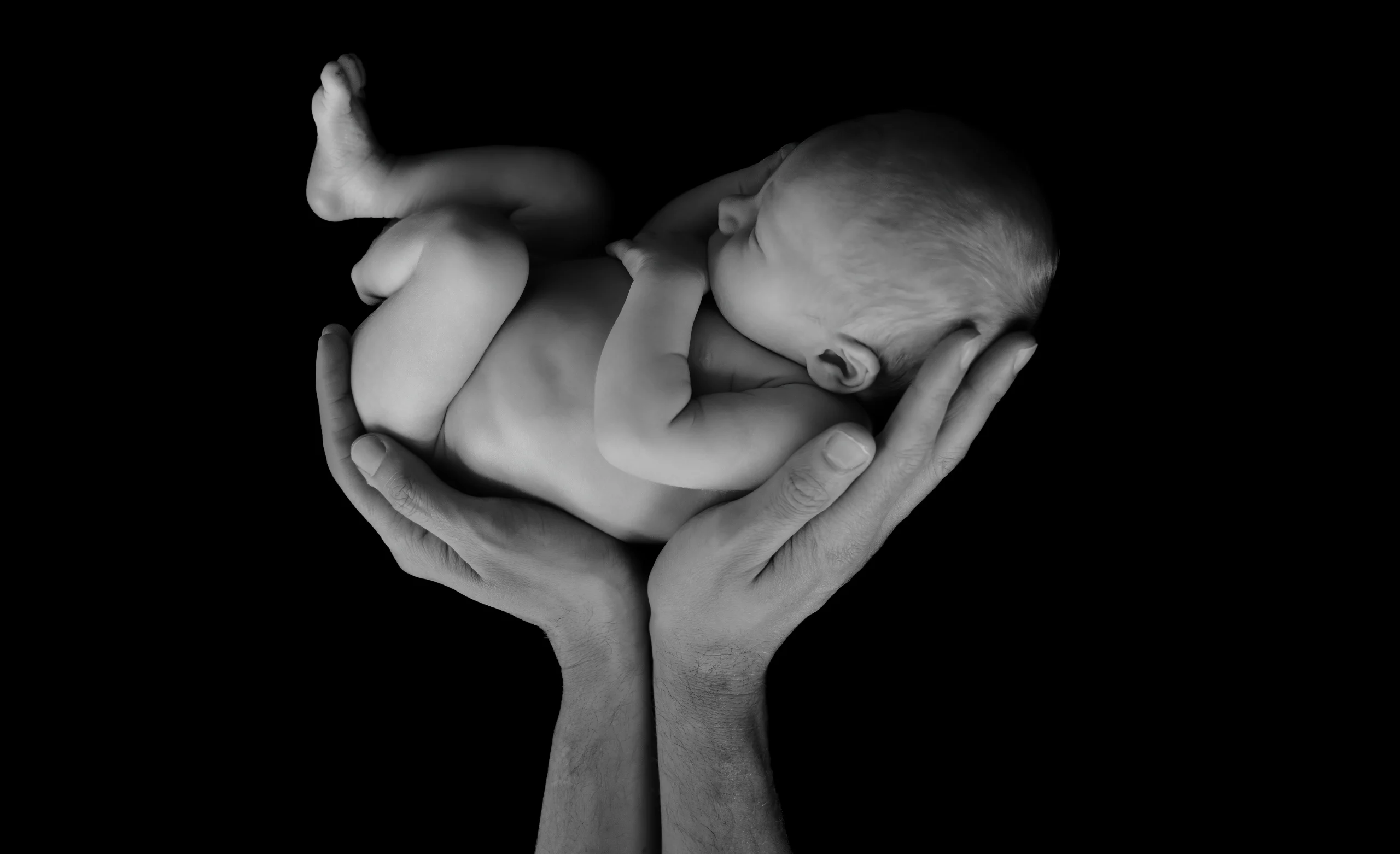 Pasgeboren baby slapend in de handen van een ouder, zwart-wit