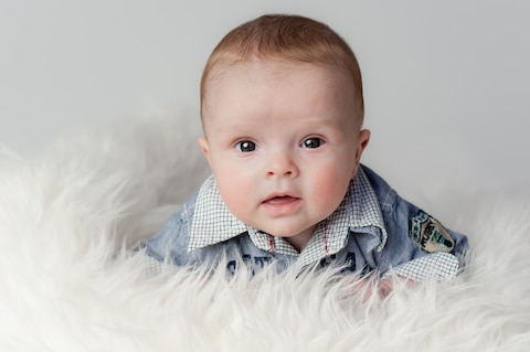 Baby van een half jaar die rechtop zit en in de lens kijkt