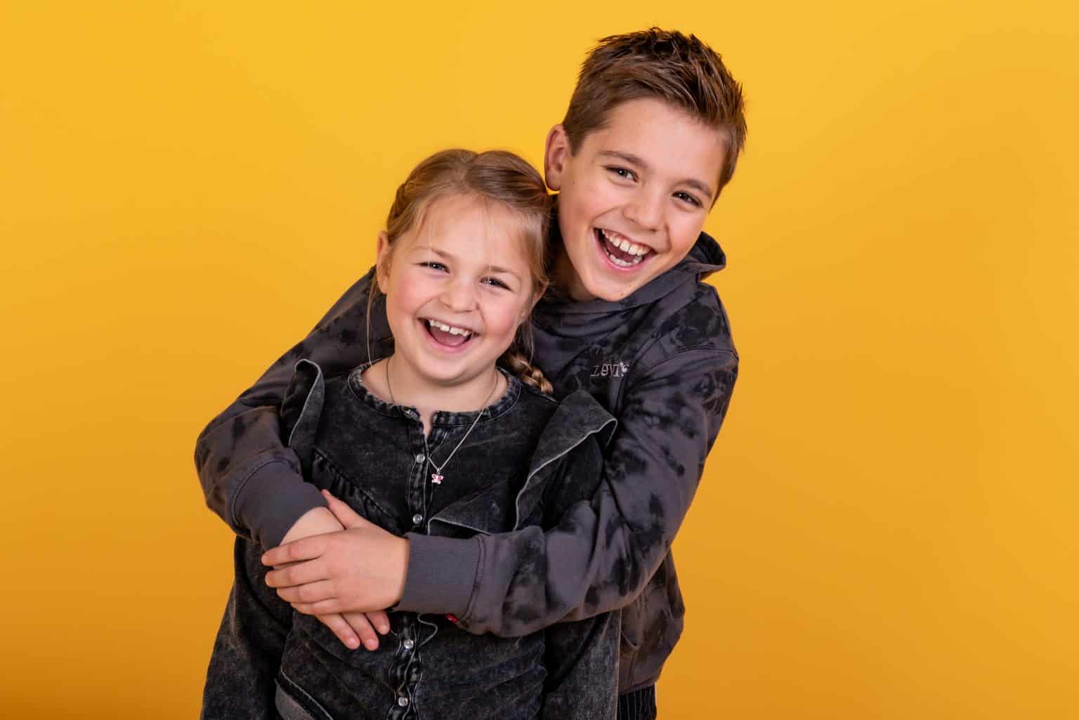 Broer en zus knuffelen tijdens een kinderfotoshoot in de studio