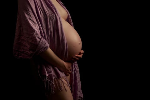 Zwangere vrouw in de studio, zijaanzicht in warm licht